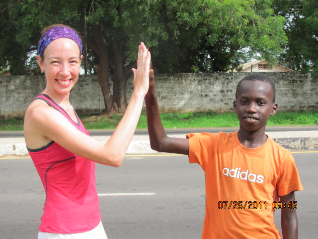 A Canadian runner high fives a young Gambian runner in Africa